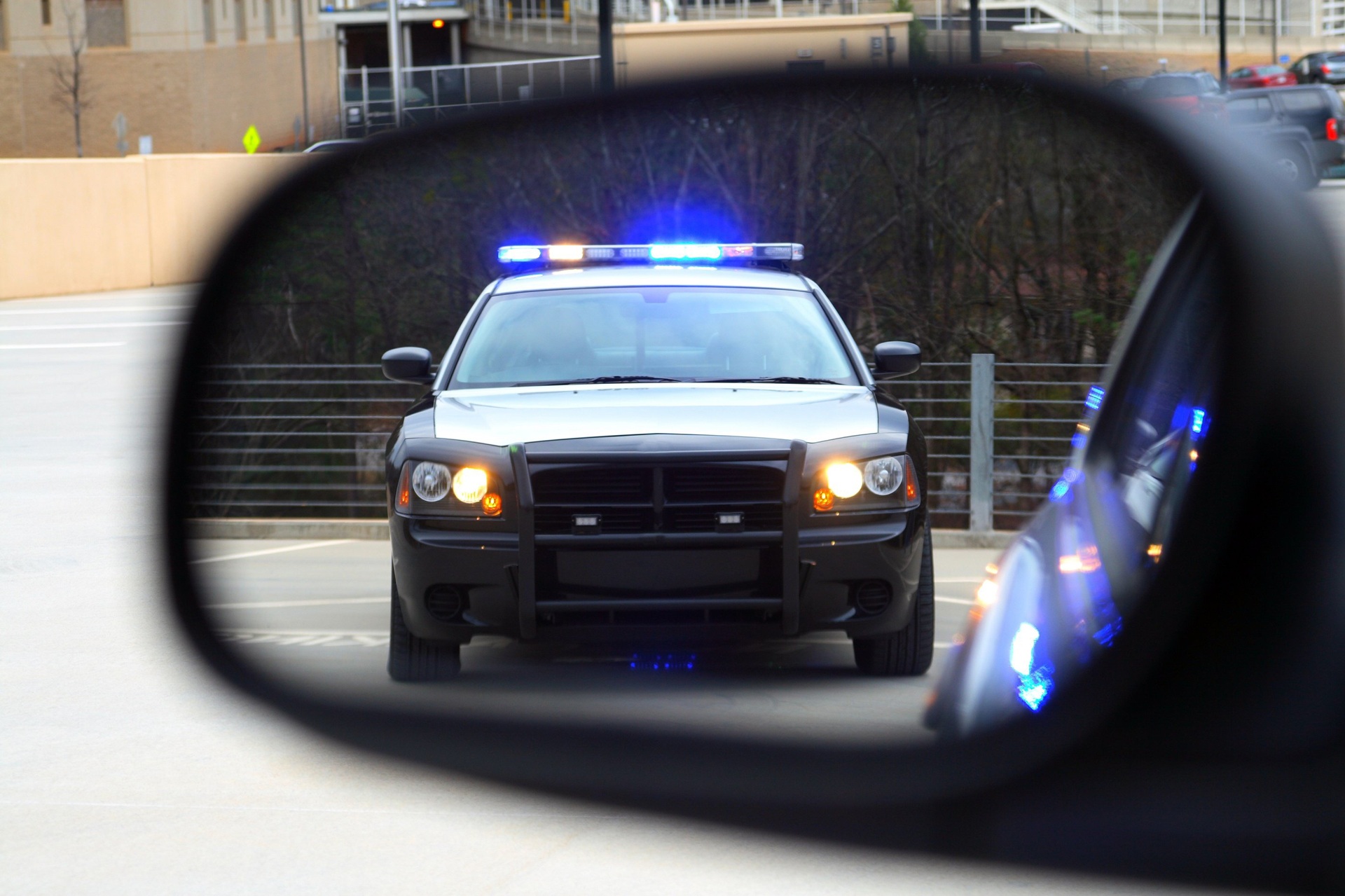 The reflection of a police car in a side view mirror.
