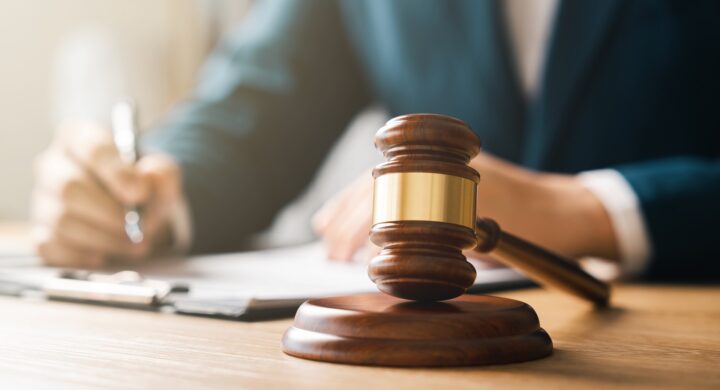 An attorney writes on a clipboard next to a gavel resting on its stand.