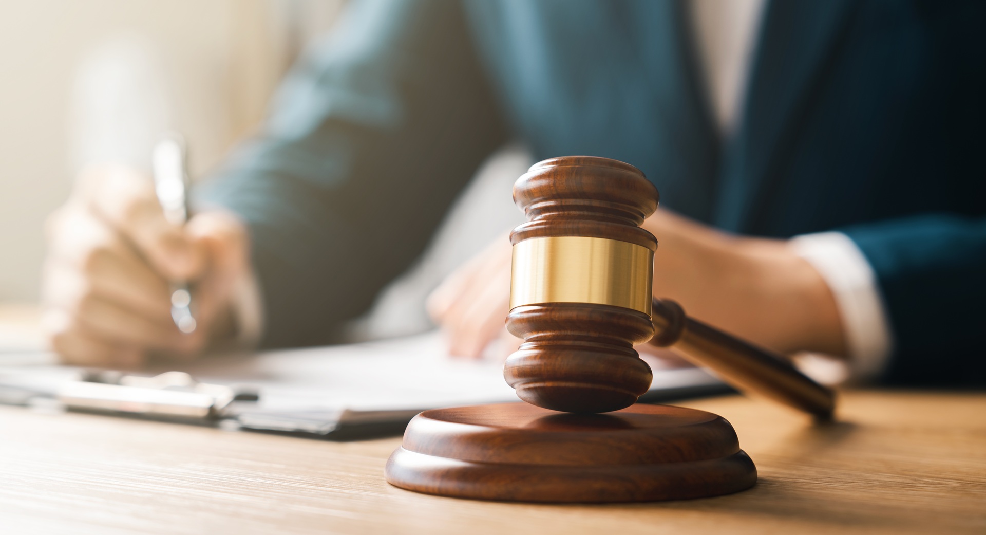 An attorney writes on a clipboard next to a gavel resting on its stand.